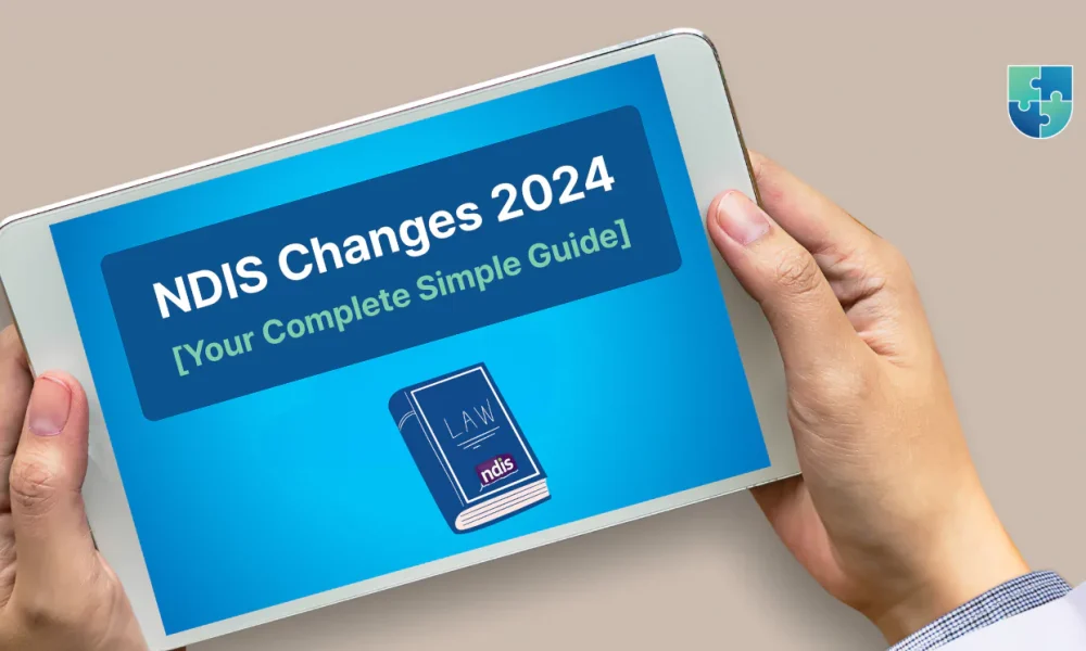 a person holding a tablet. On the screen of the tablet, there is text that reads "NDIS Changes 2024 [Your Complete Simple Guide]". Below this text, there is an illustration of a book with the word "LAW" on the cover and "ndis" written on the spine. In the top right corner of the image, there is a logo consisting of a puzzle piece design with the text "UNIQUE INDIVIDUAL SUPPORT PLAN MANAGER" next to it.